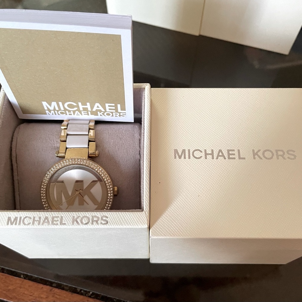 Gold Diamond plated Michael Kors watch with a white band.